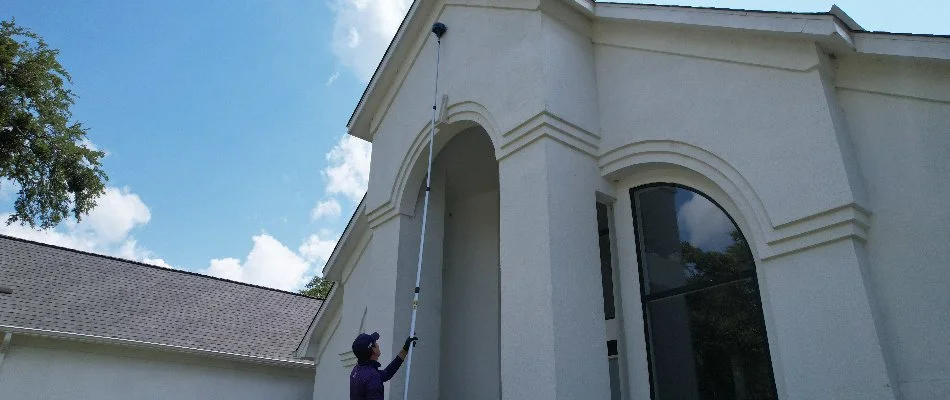 A professional extending a web pole for perimeter pest control in Fort Worth, TX.