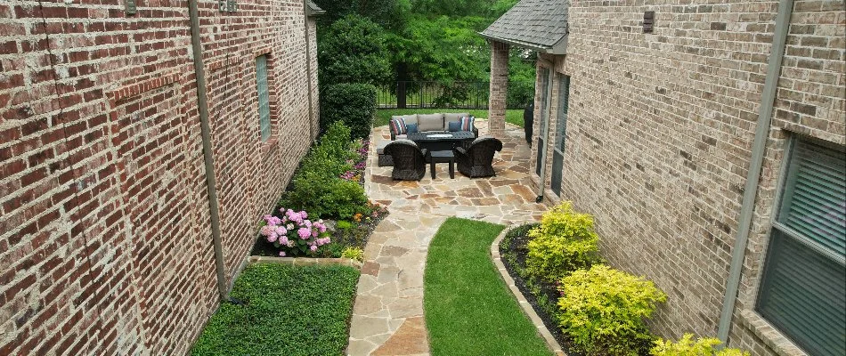 A serene view of a backyard patio surrounded by a brick wall and lush landscaping.