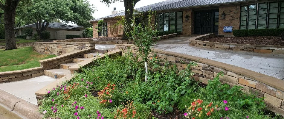 A beautifully landscaped front yard featuring stone steps leading to a brick home. 