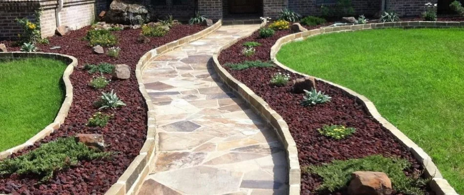 Mulched landscape bed with small plants along a walkway in Kennedale, TX.