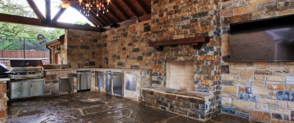 Outdoor kitchen and outdoor fireplace under a pavilion in Roanoke, TX.