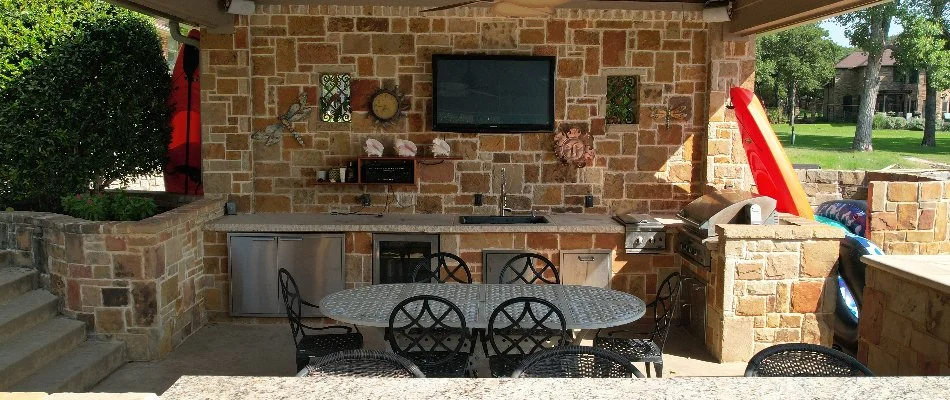 Outdoor kitchen in Richland Hills, TX, with sink, refrigerator, tables, and chairs.