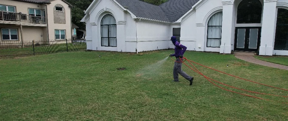 Pest control treatment being sprayed across lawn in River Oaks, TX.