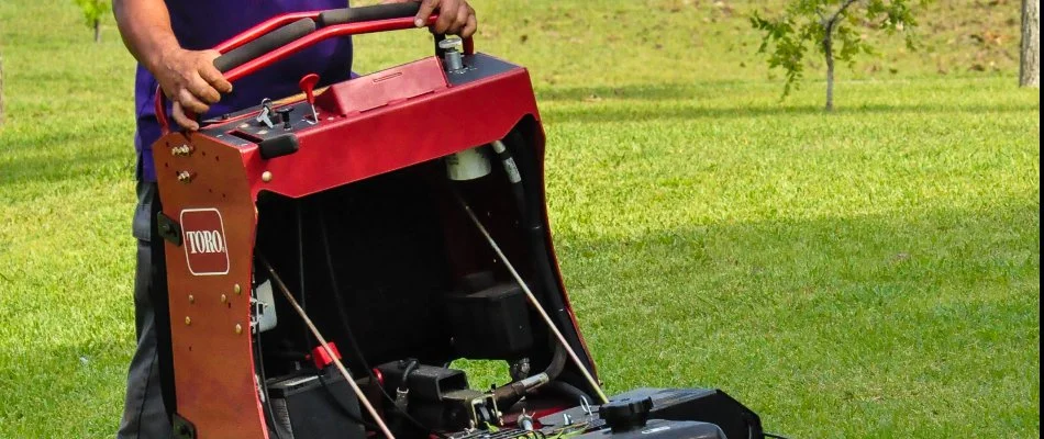 A lawn care professional operating a Toro lawn mower in a green yard, showcasing the maintenance of healthy grass and landscaping.