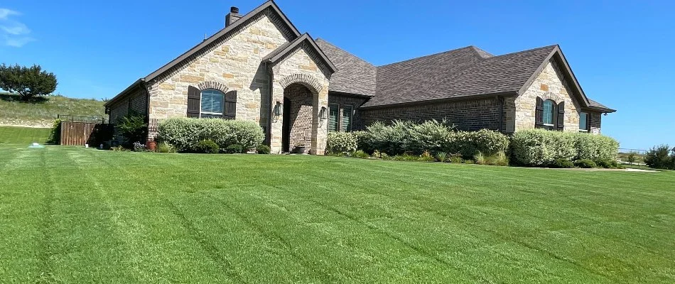 Residential property in Richland Hills, TX, with lush green lawn and shrubs.