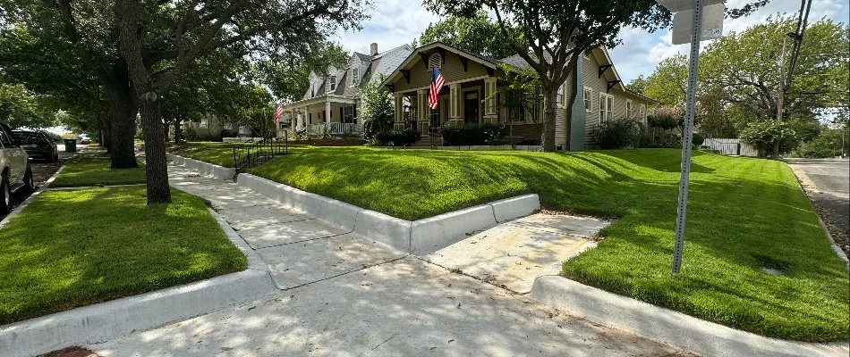 A scenic view of a suburban neighborhood featuring well-maintained homes with manicured lawns and American flags